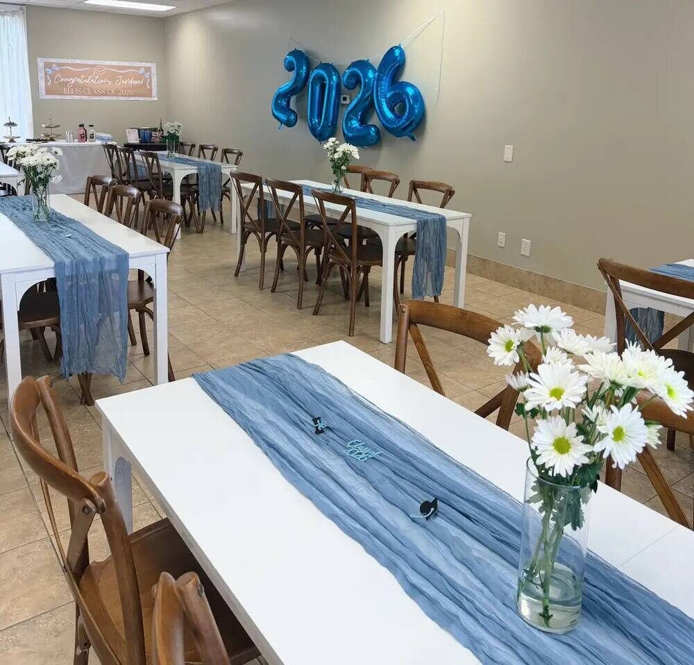 Graduation party seating with white farmhouse tables, dusty blue runners, and daisy centerpieces