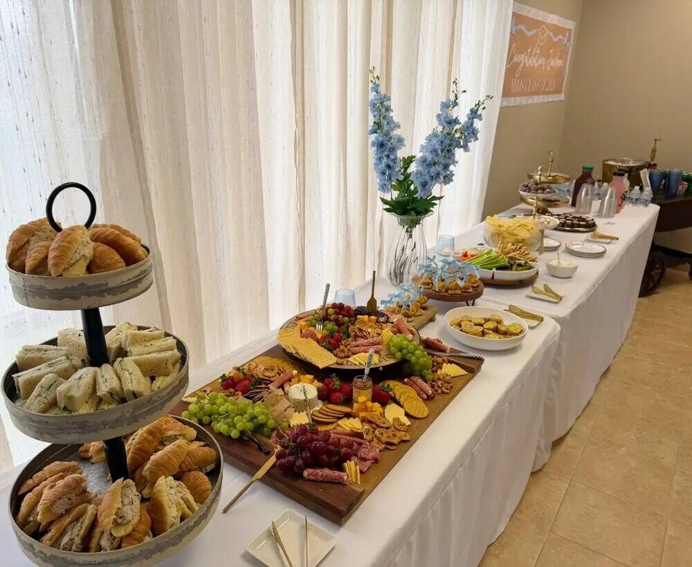 Grazing table with croissant sandwiches, charcuterie boards, and desserts on a long serving table