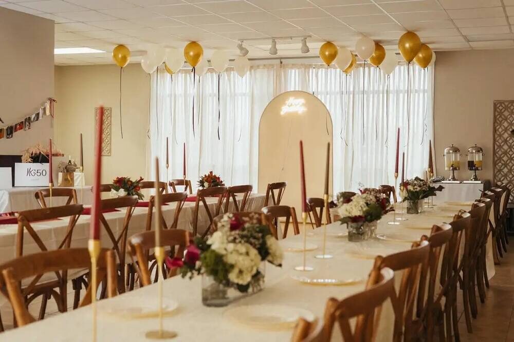 Anniversary celebration with gold and white balloons, taper candles, and floral centerpieces